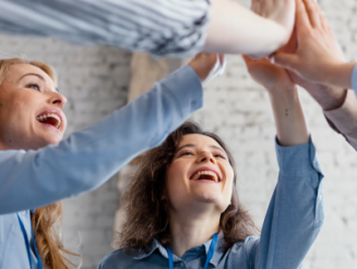 En gruppe glade mennesker som gir hverandre high-five, symboliserer samarbeid og suksess i en læringssituasjon. Perfekt illustrasjon for e-læring, der engasjement og samarbeid spiller en nøkkelrolle.