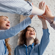 En gruppe glade mennesker som gir hverandre high-five, symboliserer samarbeid og suksess i en læringssituasjon. Perfekt illustrasjon for e-læring, der engasjement og samarbeid spiller en nøkkelrolle.