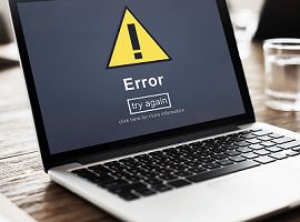 Bærbar PC som viser feilmelding med et varseltrekant-ikon og teksten 'Error – try again', symboliserer tekniske problemer eller vedlikehold av nettstedet.